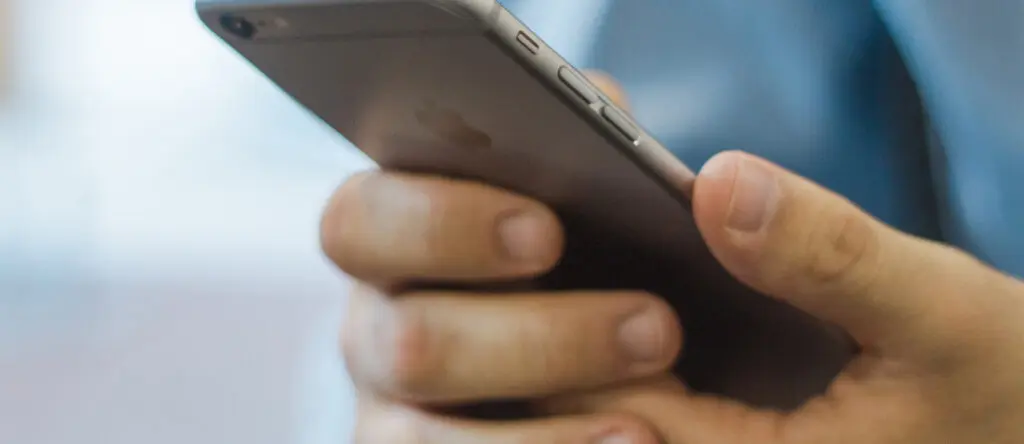 Hand holding a smartphone, emphasizing technology's role in sales enablement and leadership development.