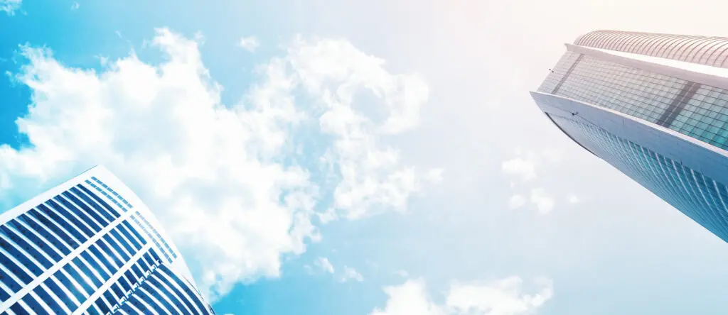 Sky view of modern skyscrapers against a bright blue sky with clouds, symbolizing business growth and leadership development.