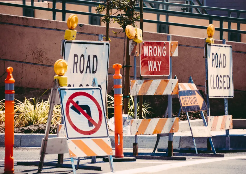 Road construction signs indicating closed roads, wrong way, and detour, symbolizing barriers to change in leadership and sales enablement.