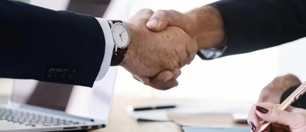 Business professionals shaking hands, symbolizing partnership and collaboration in sales leadership and enablement.