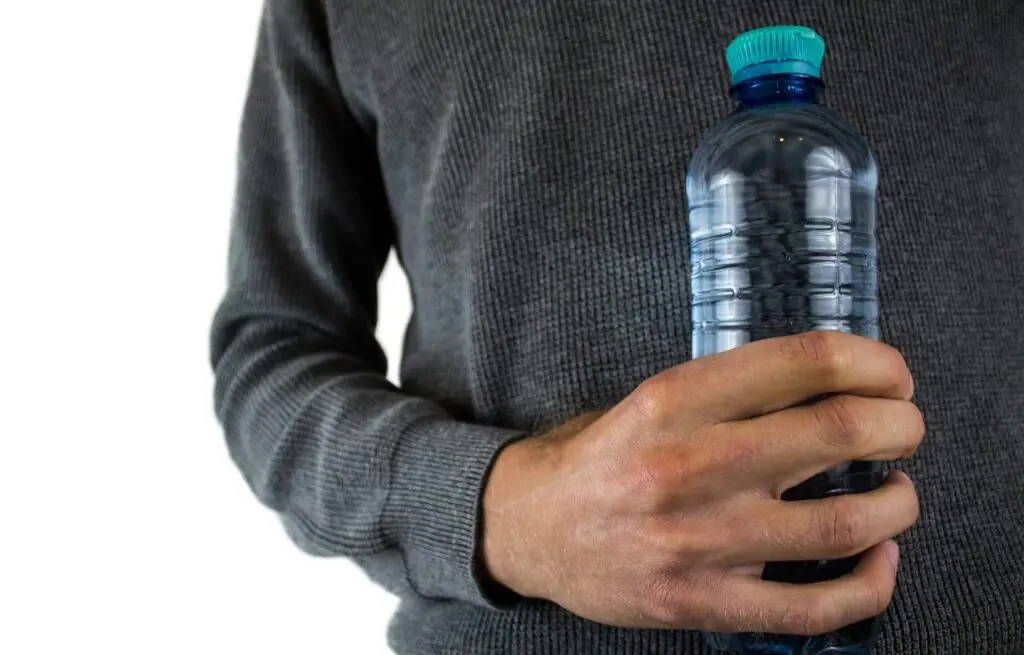 Man holding a clear water bottle, symbolizing hydration and wellness in a sales enablement context.