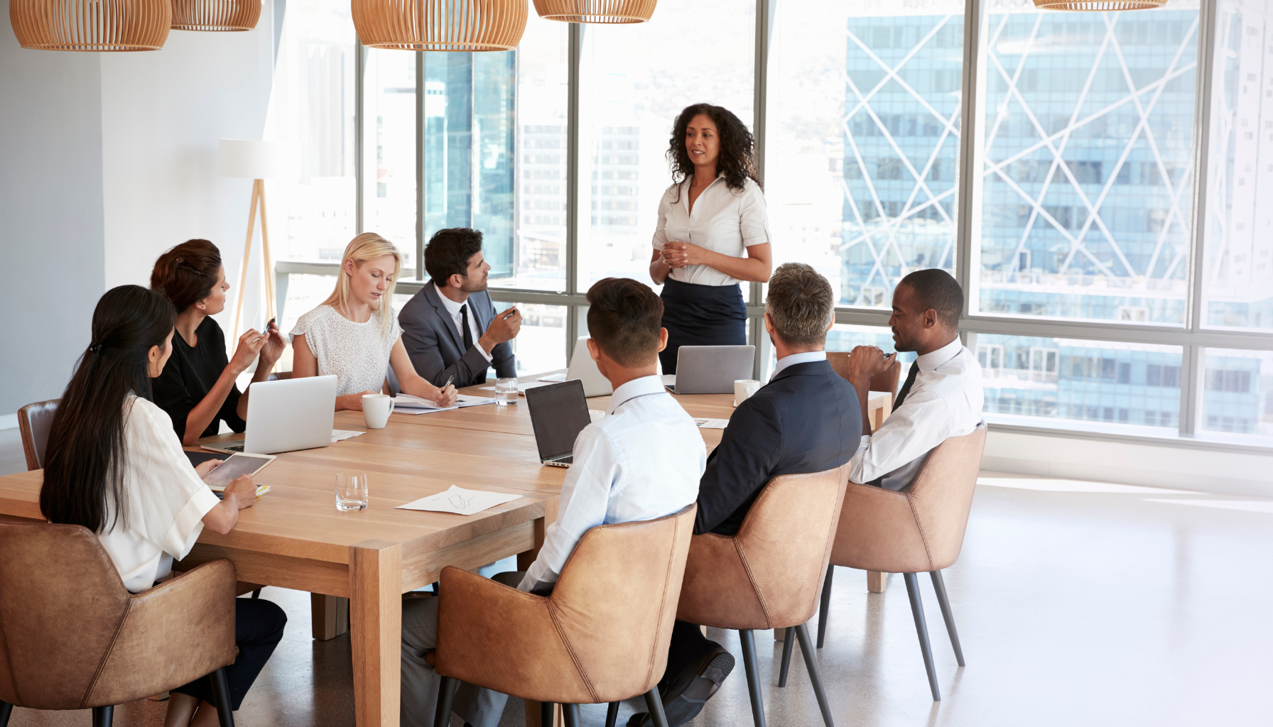 A manager coaching a team member one on one at a desk, listening rather than taking over.